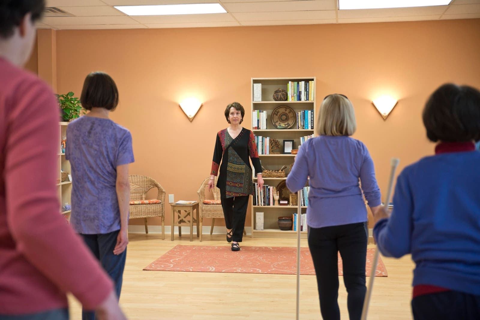 Students standing in a circle working with stretching straps while Joanne watches