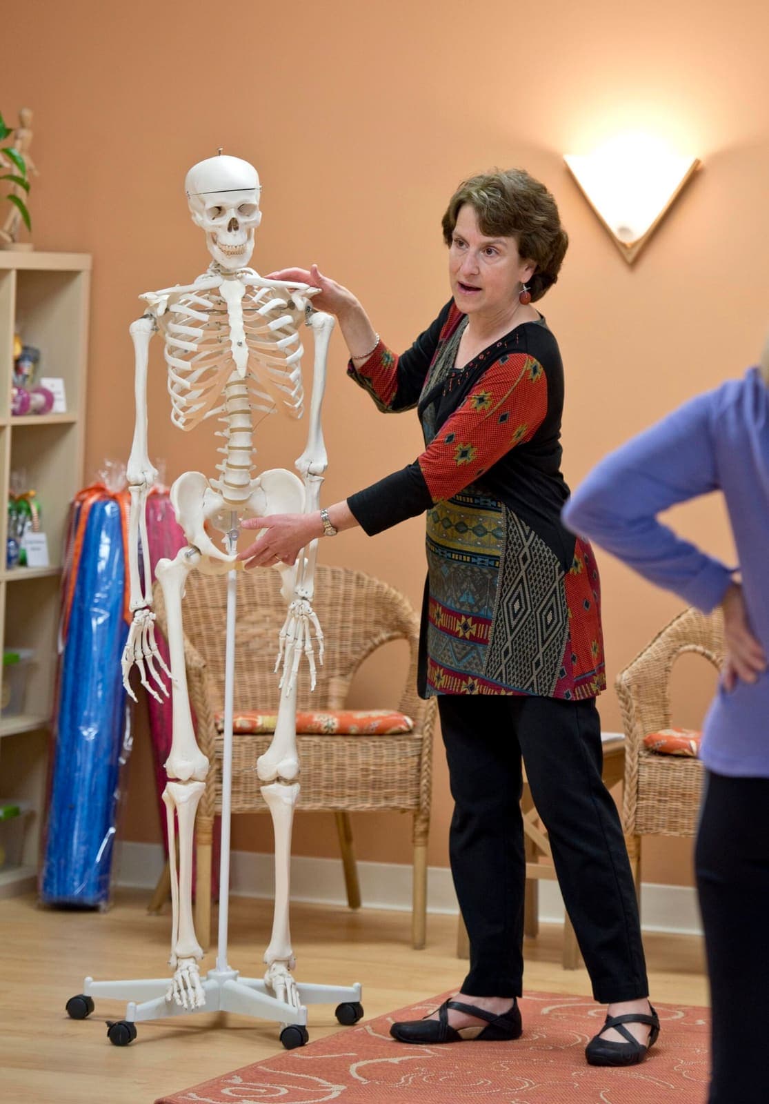 Joanne pointing out a vertebra on a life-size anatomical skeleton to a student