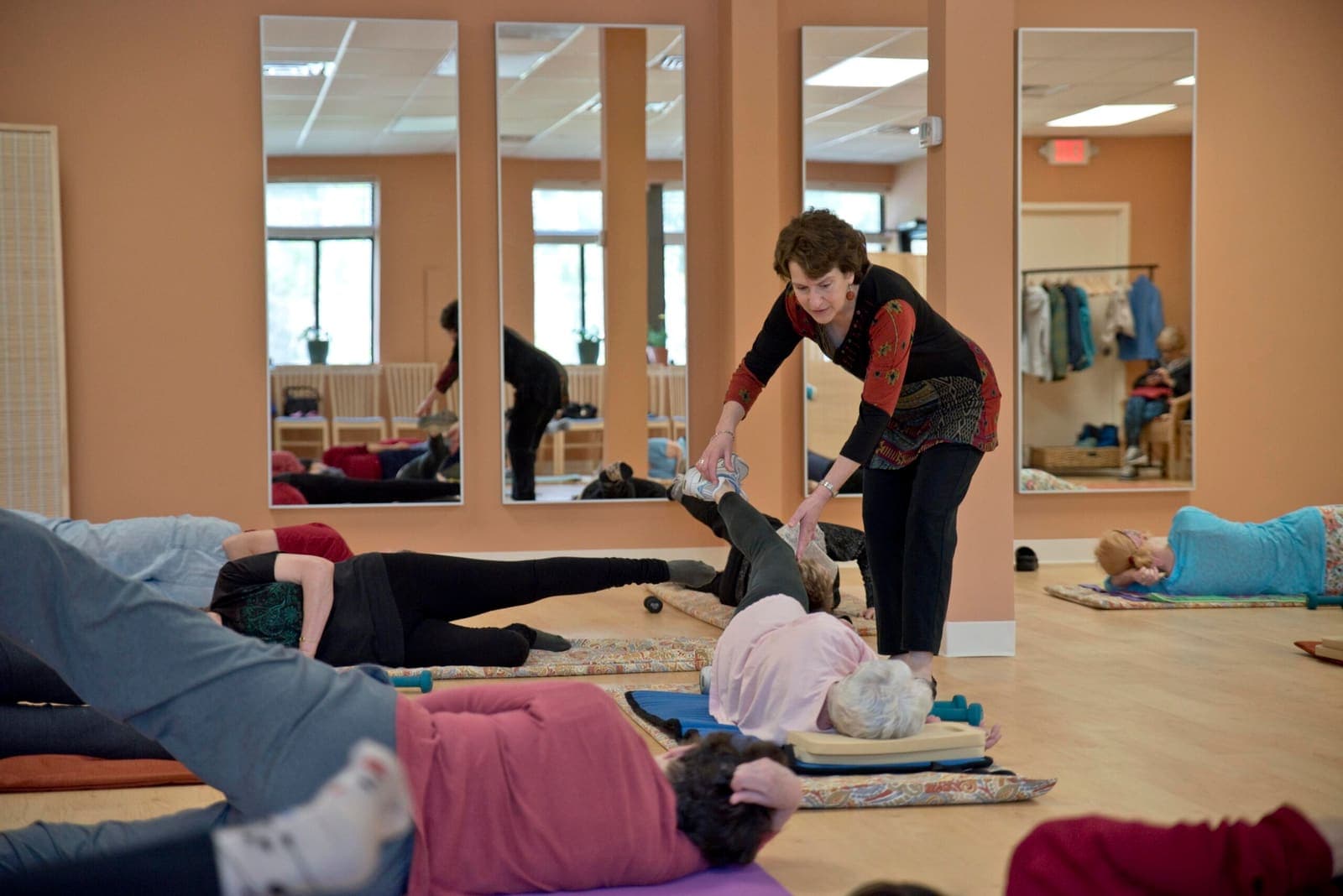 Joanne crouching to support a student's leg during a floor exercise